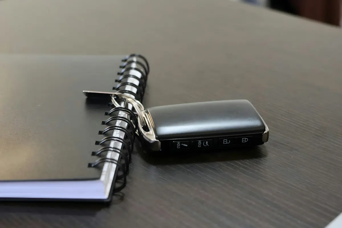 Llave de coche con mando junto a una libreta de espiral sobre una mesa