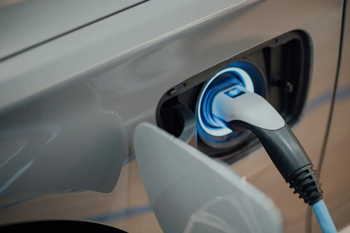 Conector de carga enchufado a un coche eléctrico plateado